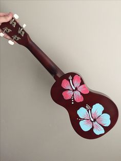 a person holding an ukulele with flowers painted on it