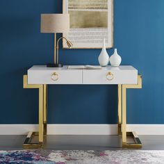 a white and gold desk with two vases on it in front of a blue wall