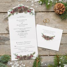 wedding stationery with pine cones and evergreens on wooden table next to christmas decorations