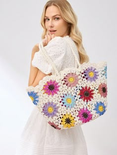 a woman is holding a crocheted bag with flowers on the front and bottom