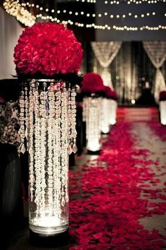 red rose petals in vases with lights and draping on the floor behind them