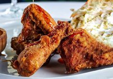 some fried food on a white plate with coleslaw and salad in the background