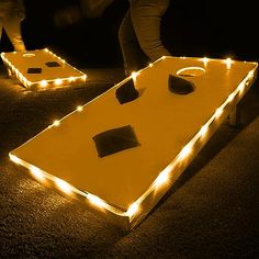 lighted cornhole game being played in the dark