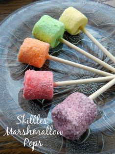 six marshmallow pops on a clear plate with the words skittles marshmallow pops