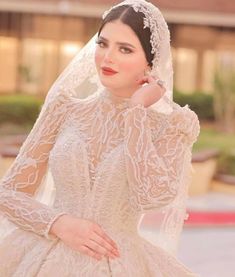 a woman in a wedding dress with a veil on her head is posing for the camera