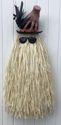 a hat, sunglasses and fake grass skirt hanging on a doorknob with a hand in it