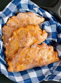 three pieces of fried chicken sitting on top of a blue and white checkered cloth