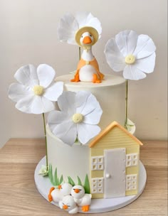 a cake decorated with white flowers and a duck sitting on top of the cake,