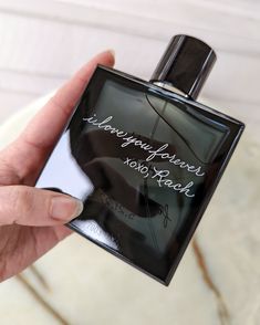 a person holding a black bottle with writing on it