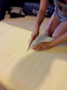 a woman kneeling on the floor cutting paper