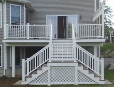 a house with white balconies on the front and second story stairs leading up to it