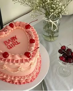 a heart shaped cake sitting on top of a table next to a vase filled with cherries