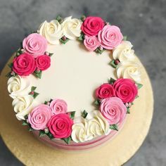 a cake decorated with pink and white flowers on top of a gold plated platter