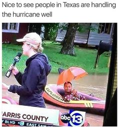 a woman holding a microphone standing next to a man in a kayak on top of a flooded street