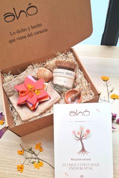 an open box filled with different items on top of a wooden table next to flowers