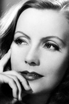 a black and white photo of a woman with her hand on her chin looking at the camera