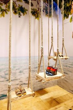 two pairs of shoes are suspended on ropes in front of an ocean wall with water