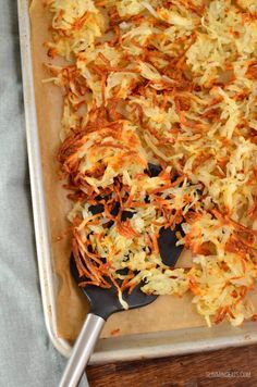 shredded carrots on a baking sheet with a spatula