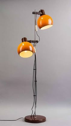 an orange lamp with two lamps on it and one light is turned on to the side