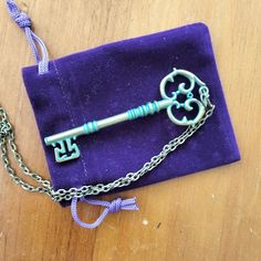 an old key is sitting on top of a purple cloth with chains attached to it