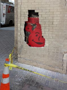 a brick wall with a hole in it that has a red fire hydrant painted on it