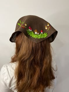 a woman with long hair wearing a hat with flowers and leaves on it's brim