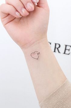 a woman's arm with a small heart tattoo on the left side of her wrist