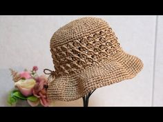 a close up of a straw hat on a stand with flowers in the back ground