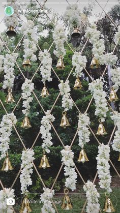 a bunch of bells are hanging on a fence with flowers and leaves all over them