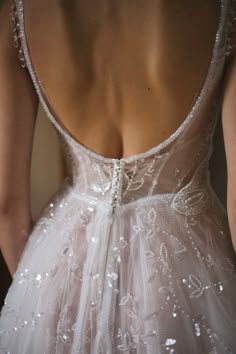 the back of a woman's wedding dress with sequins and beads on it