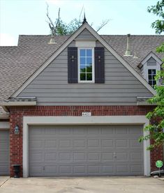 a gray house with two garage doors and windows