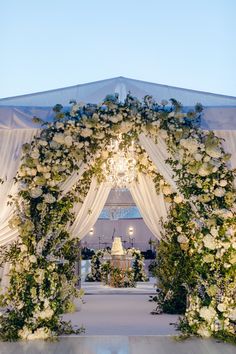 an outdoor wedding ceremony with white flowers and greenery on the aisle, decorated with chandelier