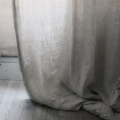 a cat sitting on the floor next to a curtain