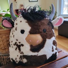 a stuffed cow sitting on top of a wooden table