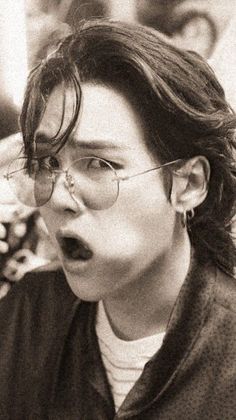 a black and white photo of a woman with her mouth wide open, wearing glasses