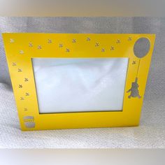 a yellow frame with stars and a teddy bear on the front is sitting on a white surface