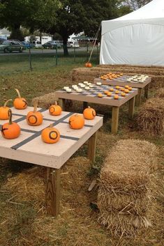 several pumpkins sitting on top of a checkerboard table in the middle of hay bales