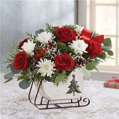 a bouquet of red roses and white daisies in a christmas sleigh with pine cones