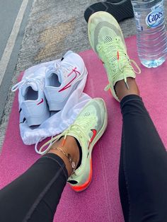 a person's feet on a pink mat with water bottle and shoes next to them