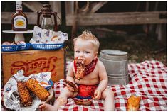 a baby sitting on a picnic blanket with food in his mouth and corn on the cob