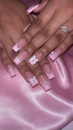 a woman's hands with pink and white nail designs on their nails, sitting on a pink satin surface