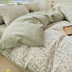 an unmade bed with pillows and a book on the pillowcase next to it