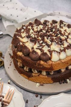 a cake with chocolate and white frosting sitting on a plate next to silverware