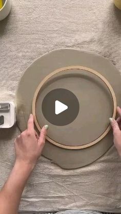 two hands are working on a large plate