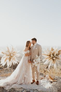 a newly married couple standing on top of a mountain