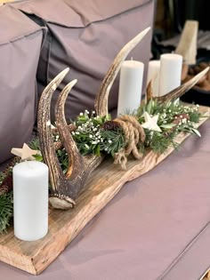 a wooden tray with candles and deer antlers on it