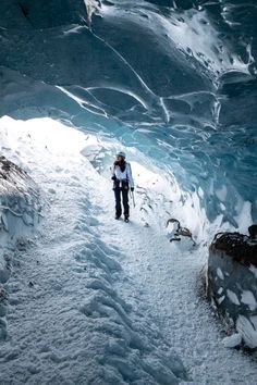 a person standing in an ice cave with snow on the ground