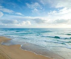 an ocean beach with waves coming in to the shore and blue sky above it on a sunny day