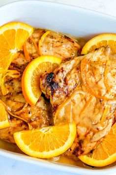 chicken with oranges and gravy in a white dish