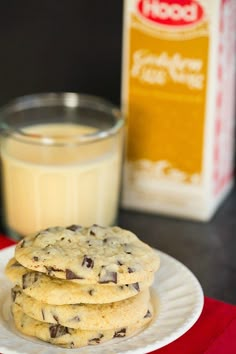 chocolate chip cookies on a white plate with a glass of milk and carton of milk in the background